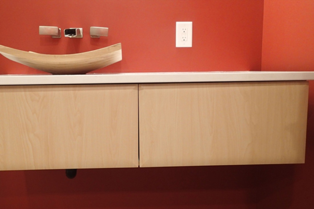 Floating wooden vanity with a wooden basin on a red wall