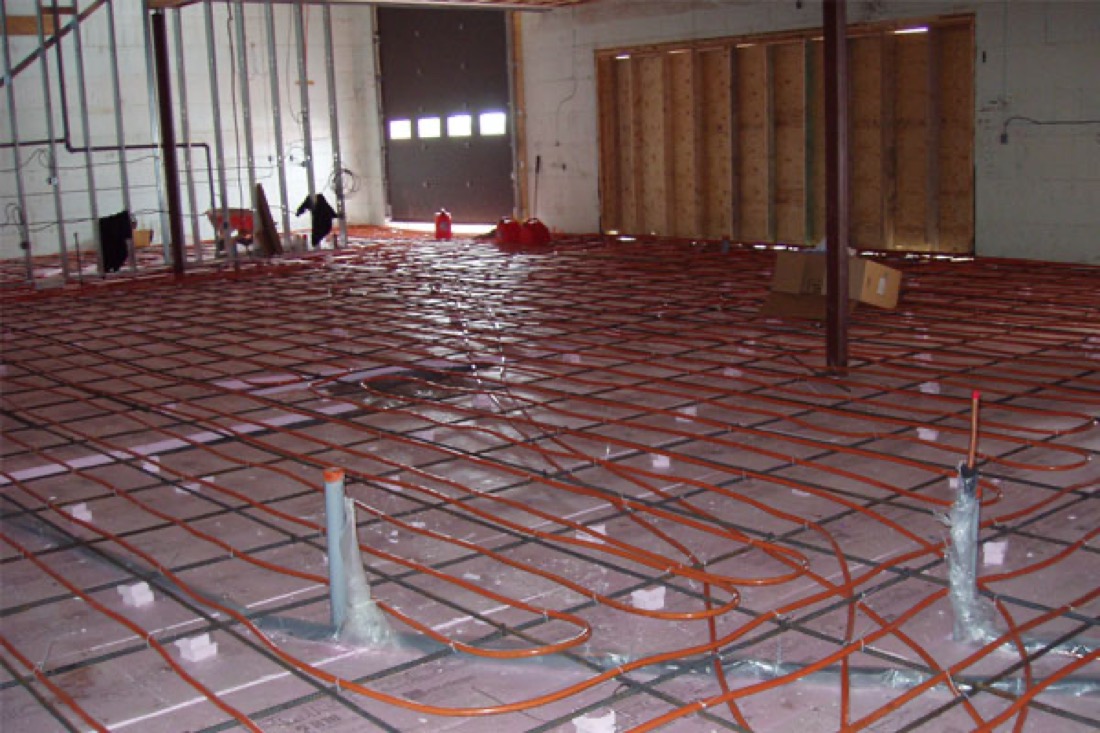 Red radiant floor heating tubing laid across a floor