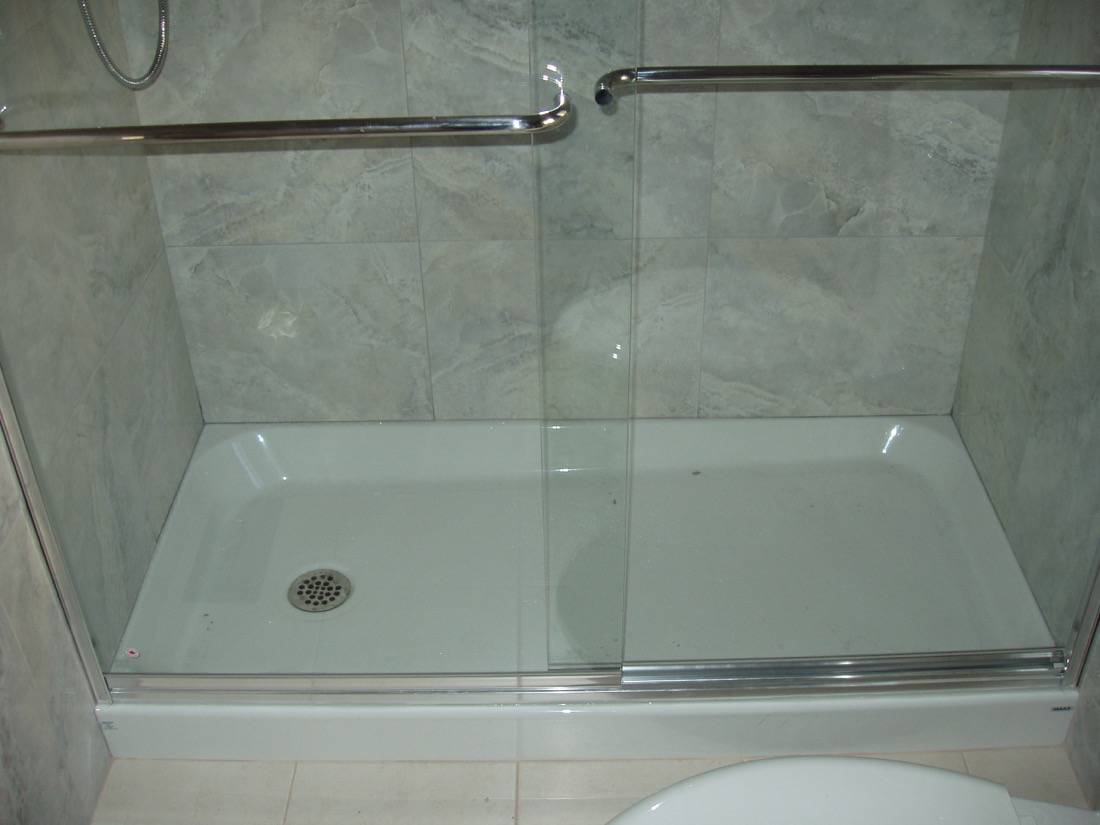 An acrylic shower base installed in a framed bathroom